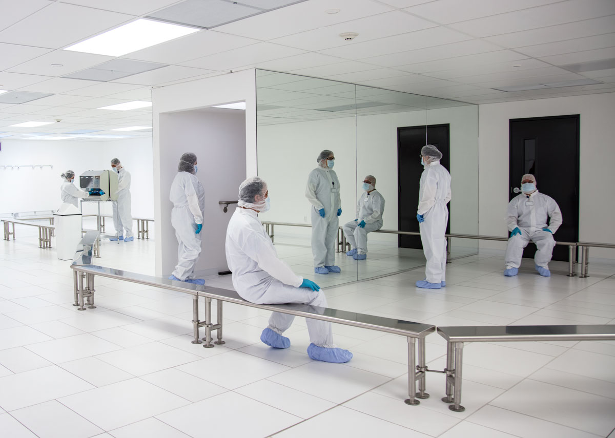 Scientists in cleanroom suits inside laboratory facility.